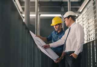 two engineers in hardhats looking at blueprints